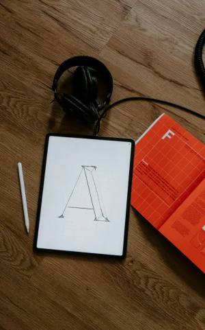 ipad with apple pencil and open book on right