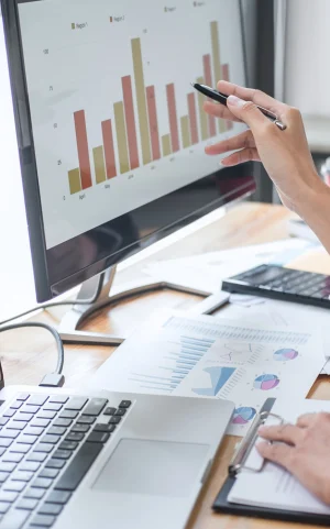 computer monitor displaying bar graphs, hand pointing to graph